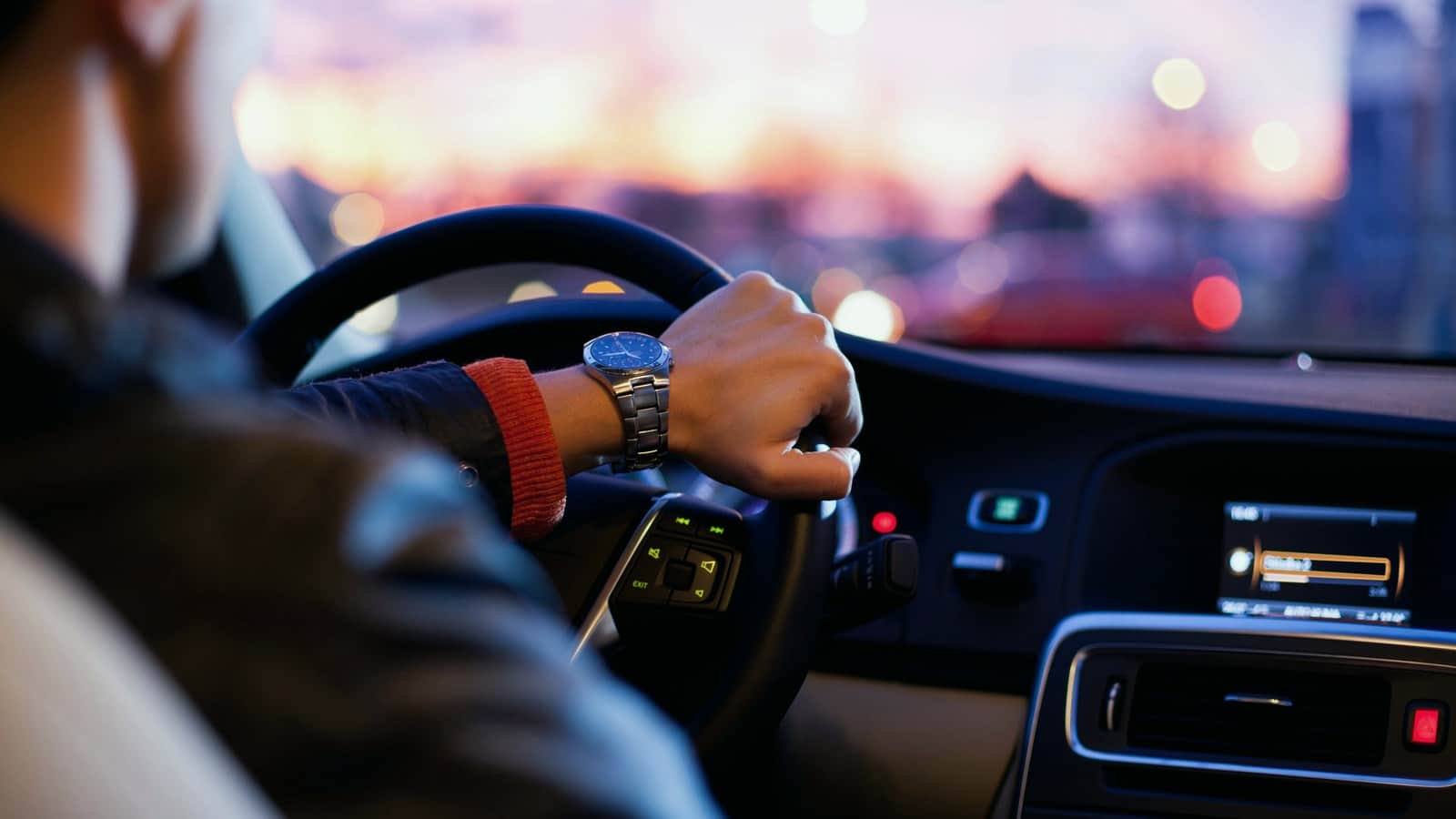 Driver holding a steering wheel at dusk
